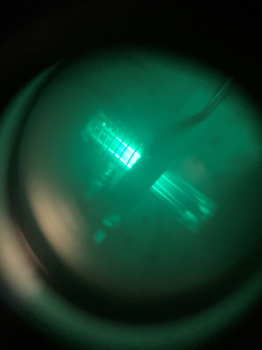 To calibrate their laser, Dragic's group takes a glass bottle containing helium and excites a plasma to create a small amount if metastable helium. They then tune the laser's wavelength so the metastable helium absorbs and emits infrared light. An infrared sensor has rendered the light green for this image.