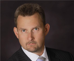 A man in a suit poses for a professional headshot