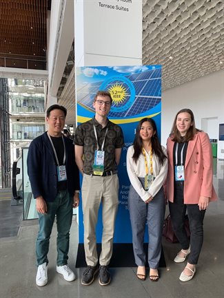 Four people stand in front of a presentation poster