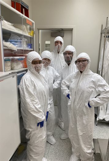 Researchers in protective body suits while standing in a laboratory